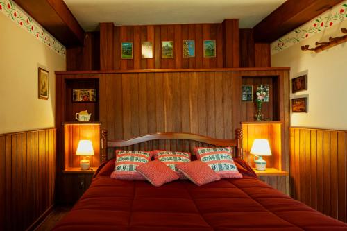 a bedroom with a bed with wooden walls and two lamps at Estalagem Entardecer da Serra in Monte Verde