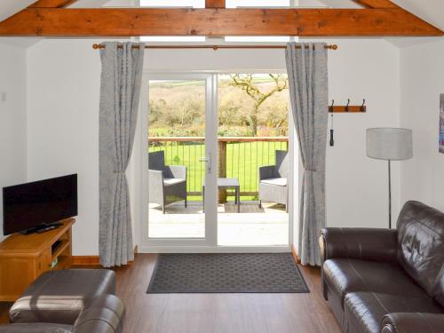 een woonkamer met een bank en een schuifdeur van glas bij Sunset in St Austell