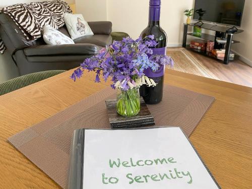 a bottle of wine and a vase of flowers on a table at Serenity- Uk38551 in Endon