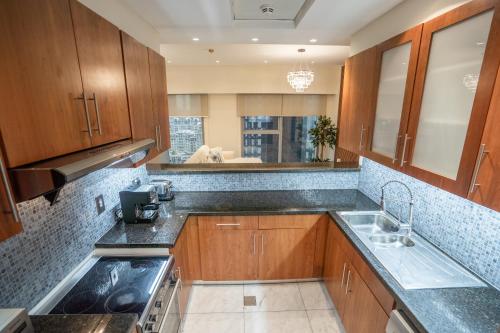 a kitchen with wooden cabinets and a sink at Nasma Luxury Stays - Central Park Tower in Dubai