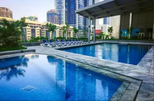 a large swimming pool with blue water in a city at Nasma Luxury Stays - Central Park Tower in Dubai