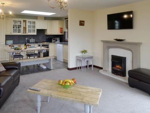 a living room with a table and a fireplace at Trebor Cottage in Annan