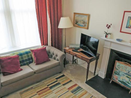 a living room with a couch and a table with a television at The Townhouse in Inverness