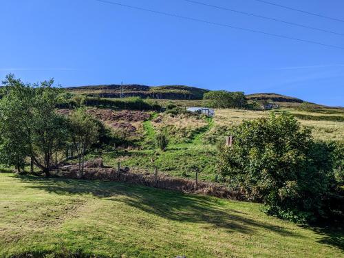 a grassy field with trees on a hill at Lephin Cottage in Glendale