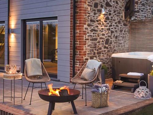 a patio with chairs and a fire pit and a tub at Acacia in West Worlington
