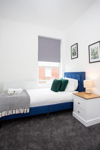 a bedroom with a blue and white bed and a window at Vacant Nests The Ropery 4BR Seafront in Seaham