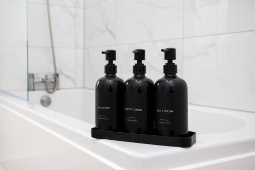 three black bottles of alcohol sitting on a bathroom sink at Vacant Nests The Ropery 4BR Seafront in Seaham