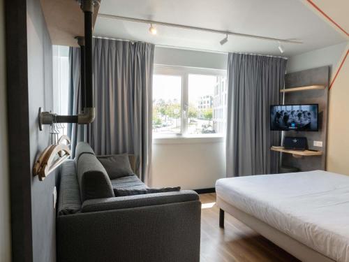 a hotel room with a bed and a couch and a window at Ibis Budget Saint Malo Centre in Saint Malo