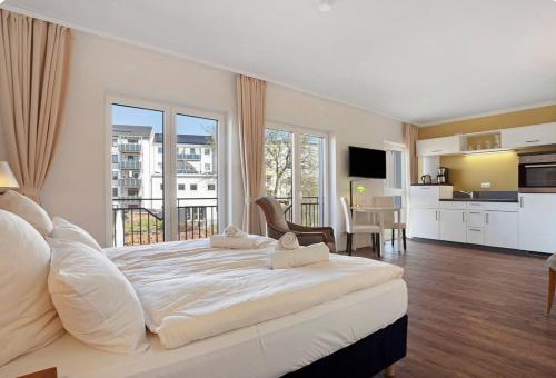 a large white bedroom with a large bed and a kitchen at Central Suites in Greifswald