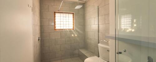 a bathroom with a toilet and a shower with a window at Rus en Vrede BackPackers Cottage! in Knysna