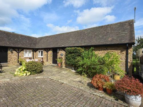 a brick house with plants and flowers in front of it at The Old Barn in Hope Bowdler