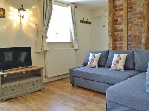 a living room with a blue couch and a tv at The Old Stables in Bakewell