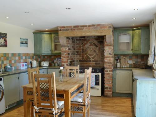 a kitchen with a wooden table and a brick fireplace at The Old Stables in Bakewell