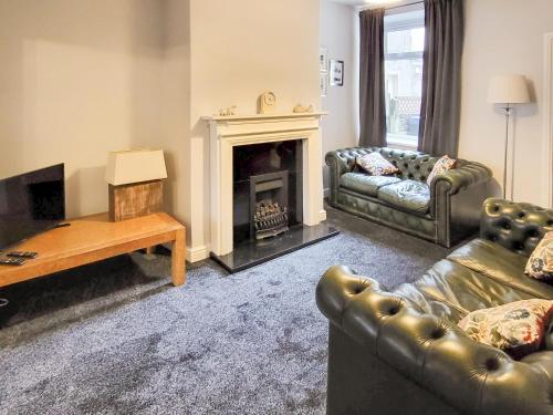 a living room with two couches and a fireplace at Lazy Cottage in Haverigg