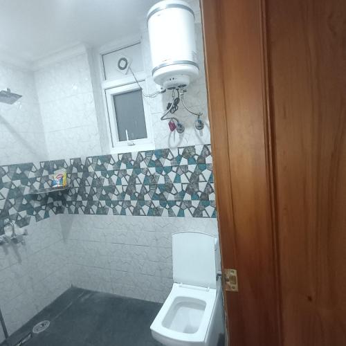 a bathroom with a toilet with a light above it at Palam residency pg in Gurgaon