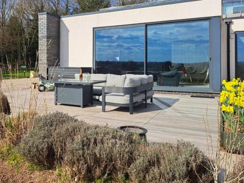 a patio with a couch and a table in front of a building at Park Barn in Whittington