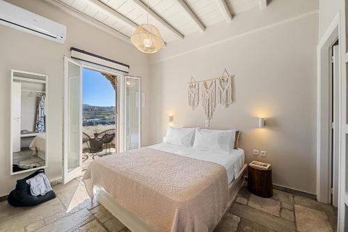 a white bedroom with a bed and a balcony at Kyma in Kardhianí