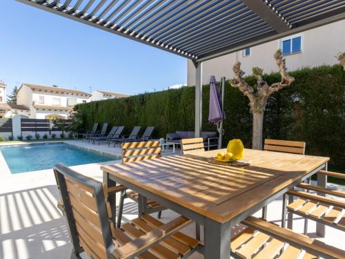 a patio with a wooden table and chairs and a pool at Holiday Home La Barca by Interhome in Cambrils