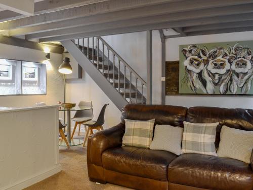 a living room with a leather couch and a staircase at Stables Grasmere in Grasmere