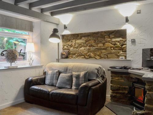 a leather chair in a living room with a stone wall at Stables Grasmere in Grasmere