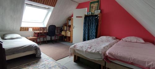a bedroom with two beds and a red wall at Ch'ti Tichenn GR34 in Saint-Michel-en-Grève