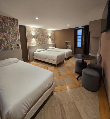 a hotel room with two beds and a table at Beaune Hôtel in Beaune