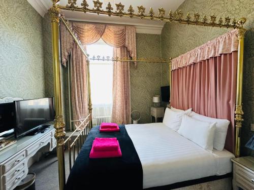 ein Schlafzimmer mit Himmelbett und Fernseher in der Unterkunft Eliza House in Edinburgh