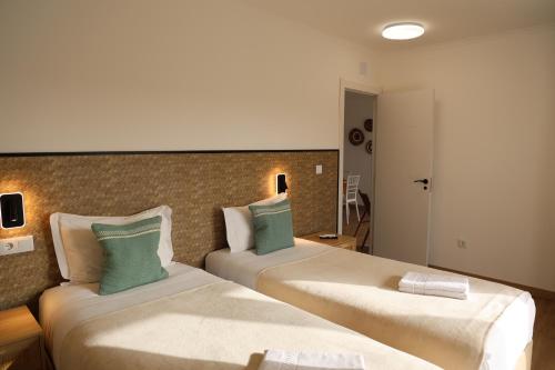 a hotel room with two beds with green pillows at Olivale Villas in Campo Maior