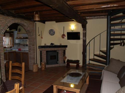 a living room with a fireplace and a staircase at La casa del Vado in Hervás