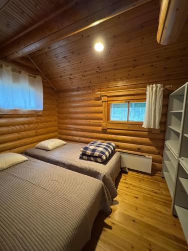 a bedroom with two beds in a log cabin at Lakeside Cottages in Rastinniemi