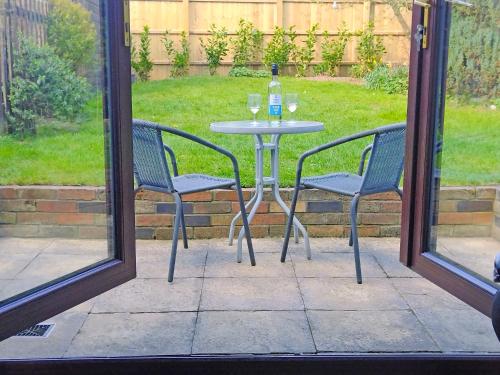 a table with two chairs and a bottle of wine at White Cottage in Hemingby