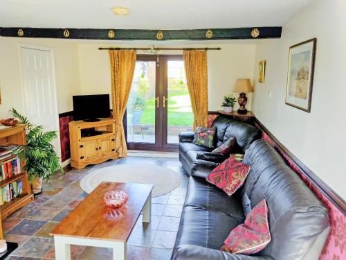 a living room with a leather couch and a table at White Cottage in Hemingby