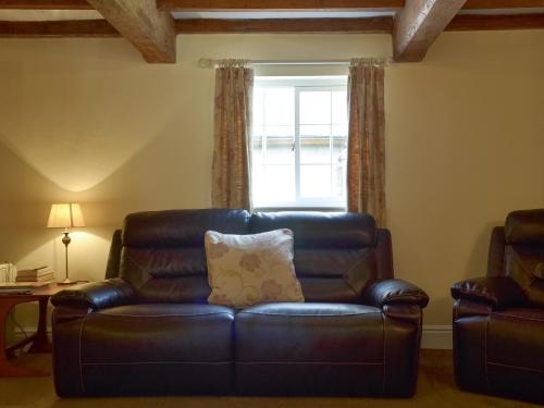 a leather couch in a living room with a window at Burdettes Cottage - 25349 in Findern