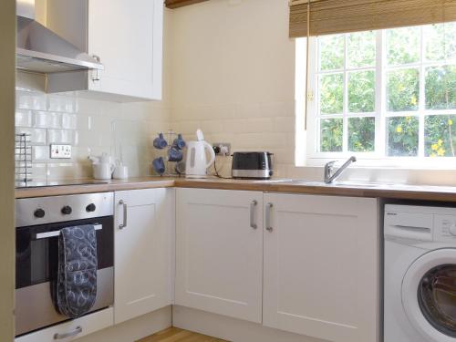 a white kitchen with a sink and a dishwasher at Burdettes Cottage - 25349 in Findern