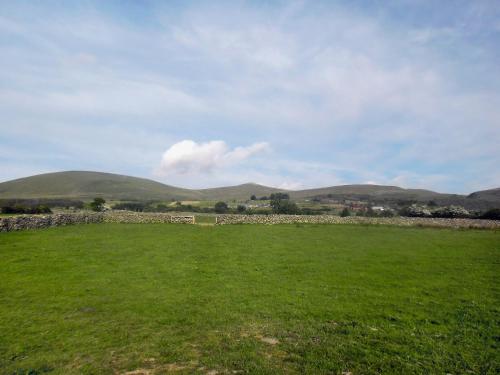 a field with a stone wall and mountains in the background at Y Gorlan - Uk6403 in Llanllechid