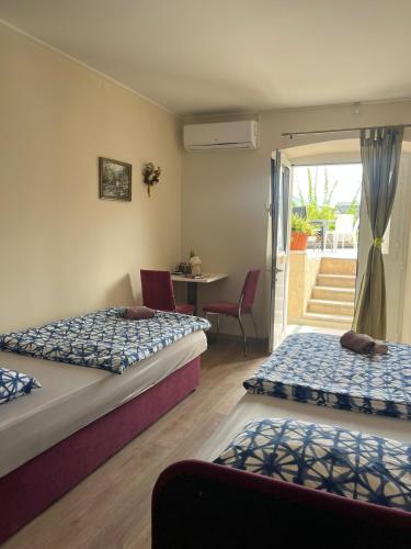 a bedroom with two beds and a table and a balcony at Rooms Lami in Dubrovnik