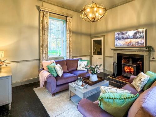 a living room with purple couches and a fireplace at Falconer's Lodge in Didlington