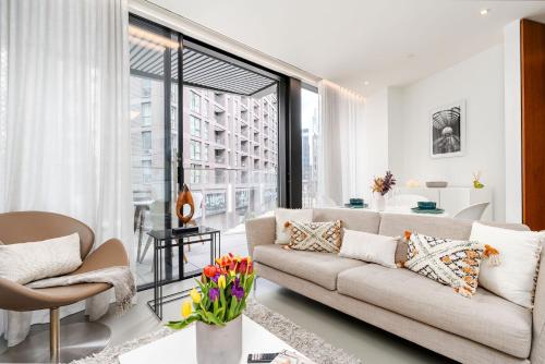 a living room with a couch and a large window at Designer Stay at Kings Cross Gasholders with Balcony in London