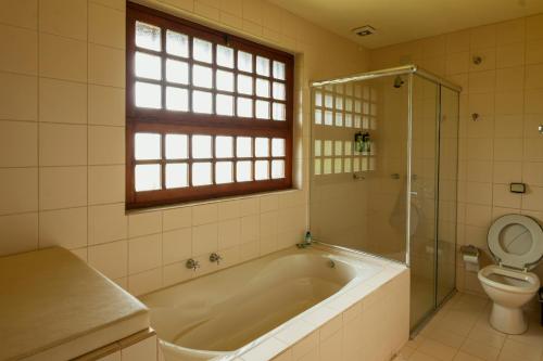 a bathroom with a tub and a toilet at Estalagem Entardecer da Serra in Monte Verde