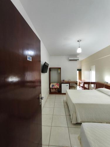 a hotel room with two beds and a door at Foz Presidente Economic Hotel in Foz do Iguaçu