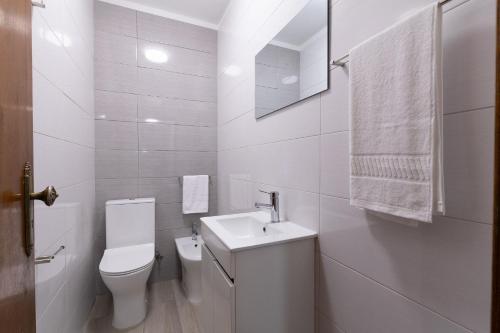 a white bathroom with a toilet and a sink at Gerês Home Nature in Geres