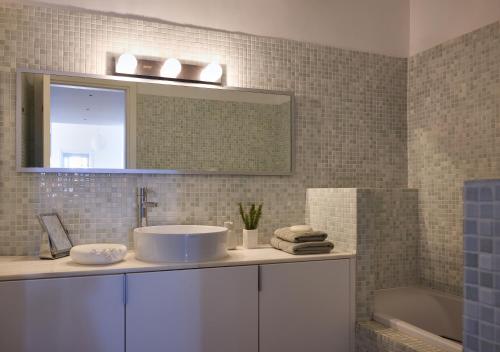 a bathroom with a sink and a mirror and a tub at Villa Litharia, enchanting location and view in Ioulis