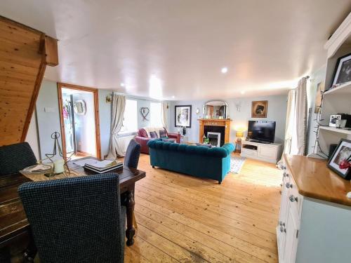 a living room with a blue couch and a tv at Cute Quirky Cottage in Llandow