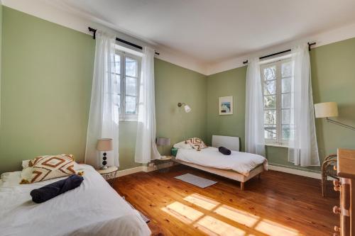 two beds in a room with green walls and windows at L'Estanquet - Maison d'Hôtes in Gardouch