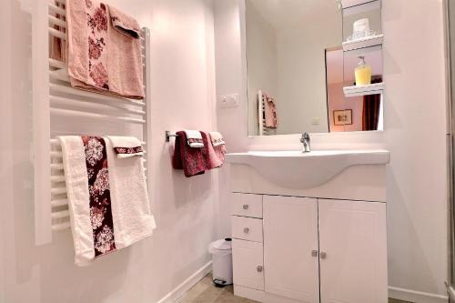 a white bathroom with a sink and a mirror at Le Moulin du Bignon in Lassy
