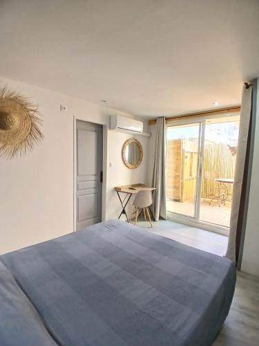 a bedroom with a bed and a table and a balcony at Hôtel Quai d'Azur in Le Grau-du-Roi