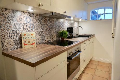 a kitchen with white cabinets and a wooden counter top at Lykke in Wrixum