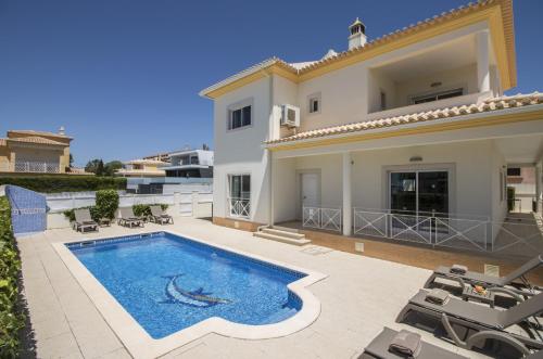 a villa with a swimming pool in front of a house at Villa Maresia by Algarve Holidays in Galé