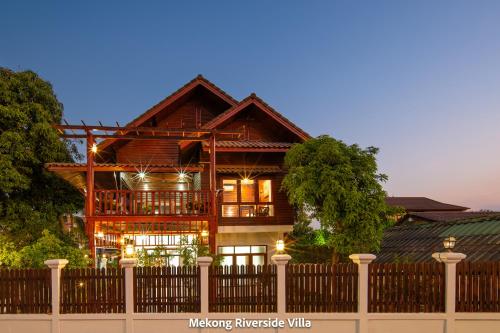 a wooden house with a fence in front of it at Mekong Riverside Villa in Vientiane