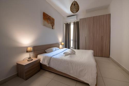 a bedroom with a bed and a lamp on a night stand at Bayview Seafront 5A in St. Julianʼs